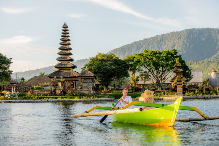 Young Couple Paddling On A Wooden Boat At Pura Ulun Danu